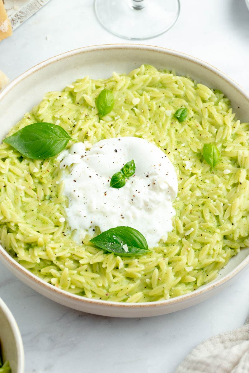 Orzo with zucchini cream on a plate with burrata and basil.