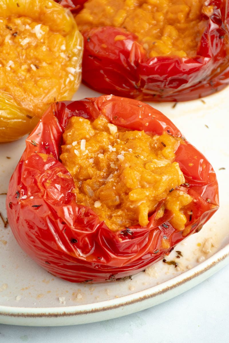 Peppers stuffed with an ultra-creamy tomato risotto on a plate.