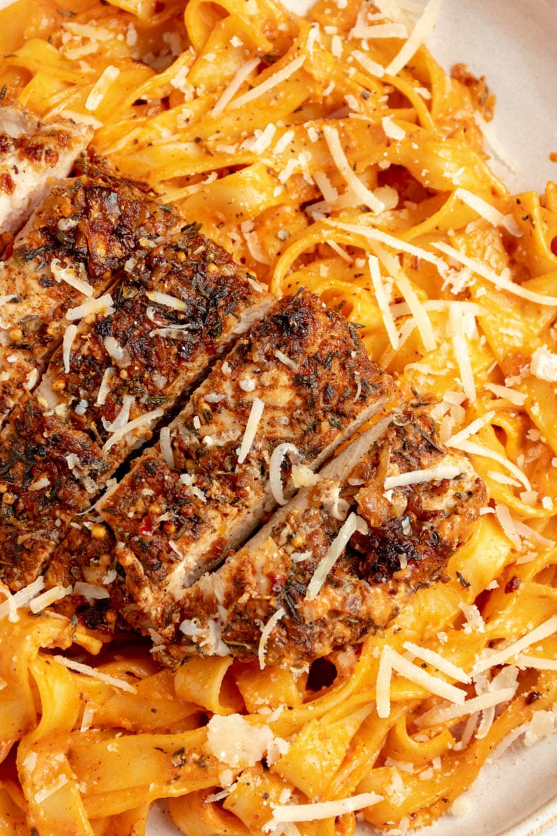 Cajun chicken with creamy pasta and Parmesan cheese on a plate.