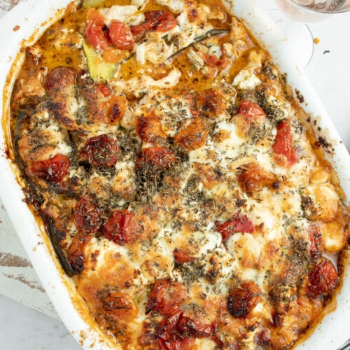 Lasagnes de courgette dans un plat blanc avec deux verres de rosé.