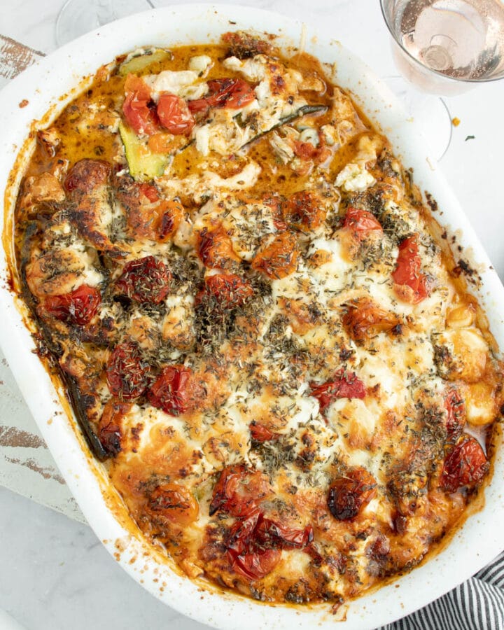 Lasagnes de courgette dans un plat blanc avec deux verres de rosé.