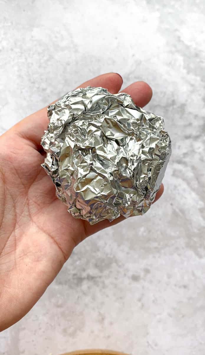 Head of garlic wrapped in aluminum foil.