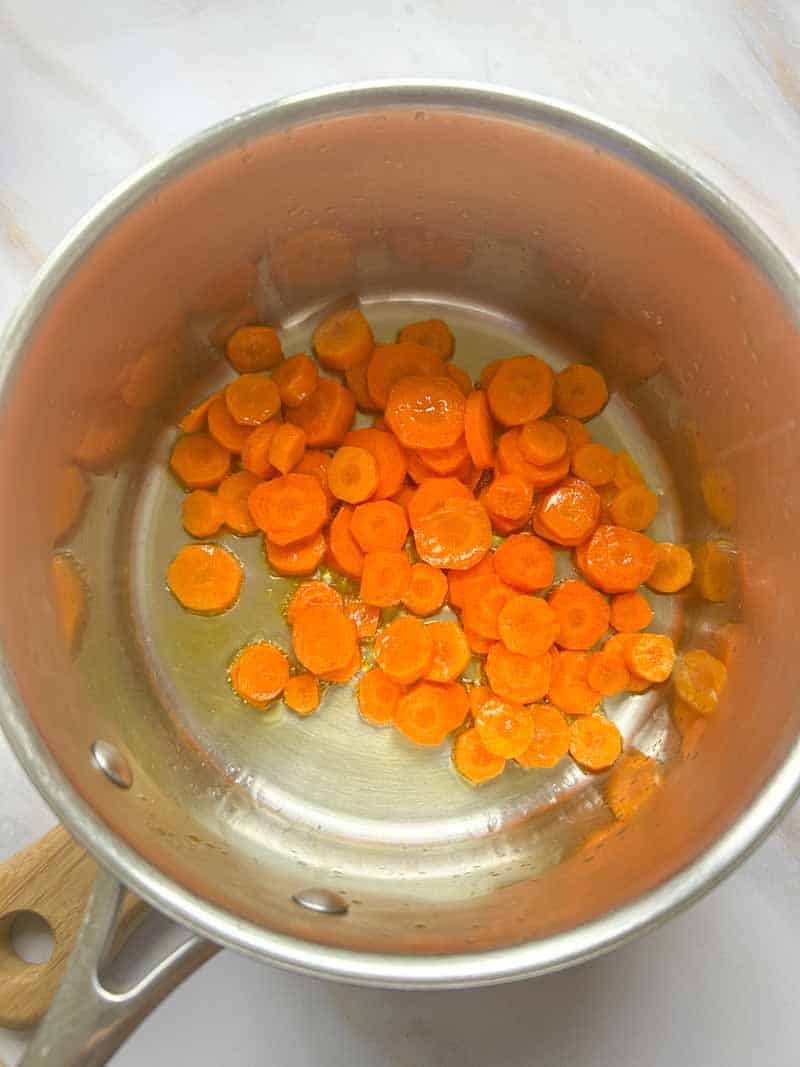 Ajout des lamelles de carotte dans une casserole.