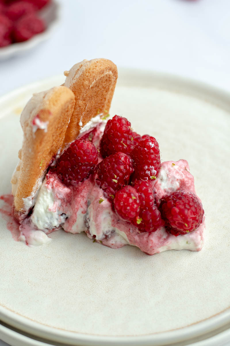 Slice of raspberry charlotte in a cream dish.