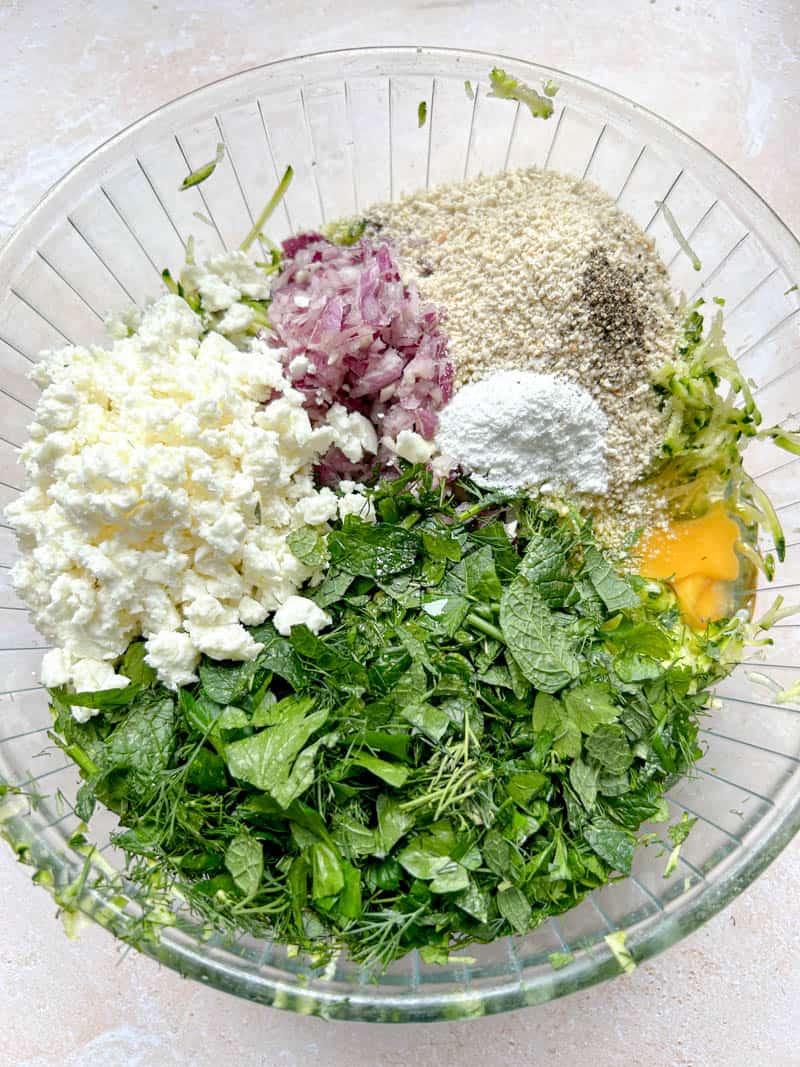 Add other ingredients: herbs, feta cheese, red onion, breadcrumbs, baking powder and egg.