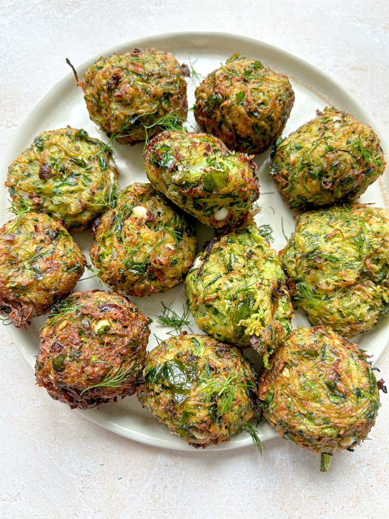 All zucchini croquettes on a plate, after cooking.