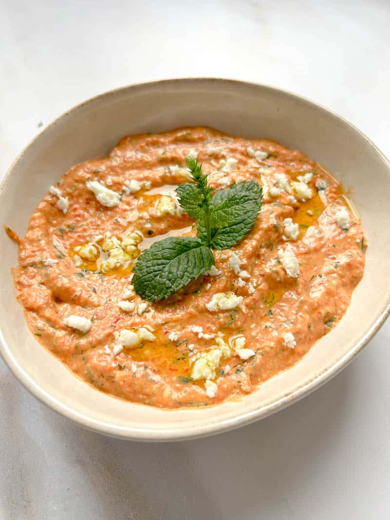 Ktipiti in a bowl with a mint leaf, crumbled feta and a drizzle of olive oil.