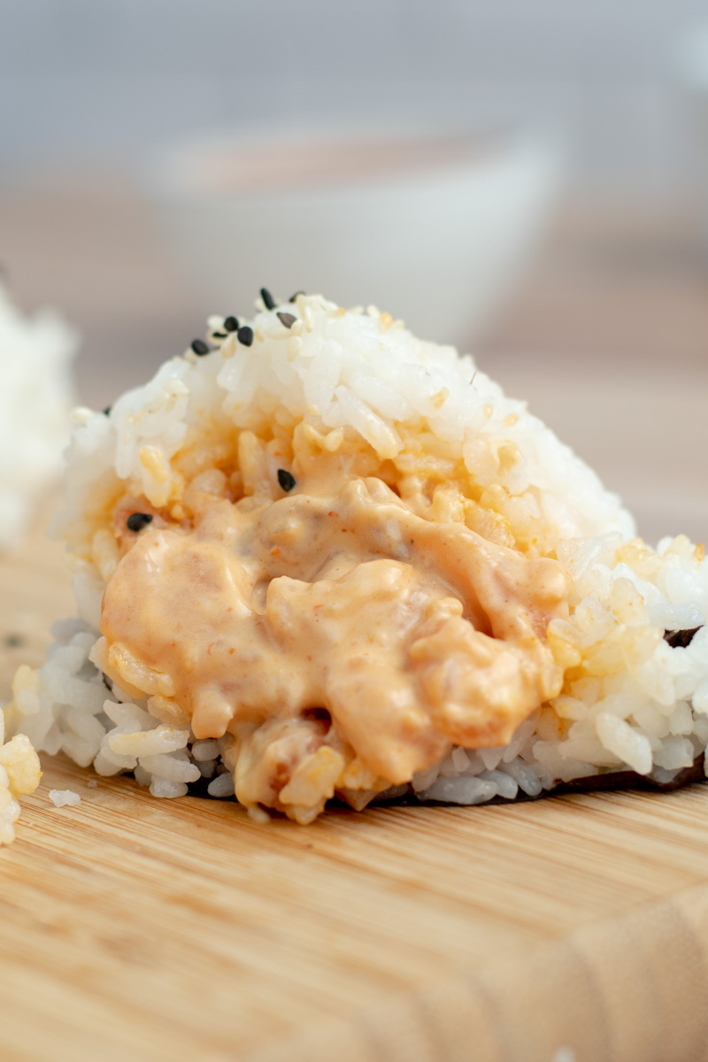 Onigiri coupé en deux, avec le saumon et la spicy mayo qui sortent.