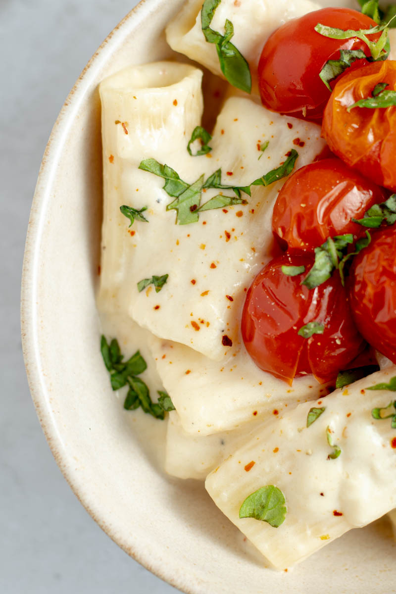 Creamy garlic confit pasta with cherry tomatoes in a bowl.