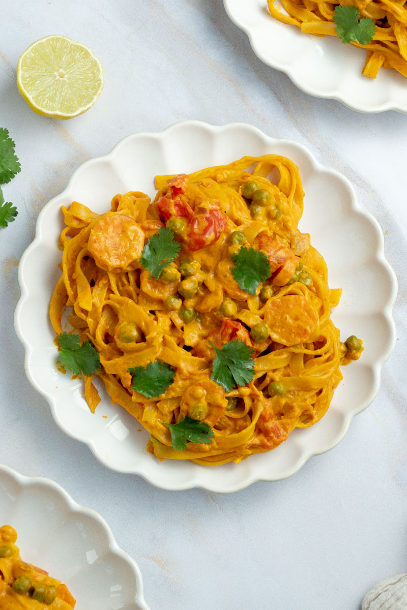 Curry pasta in a white plate with coriander leaves.