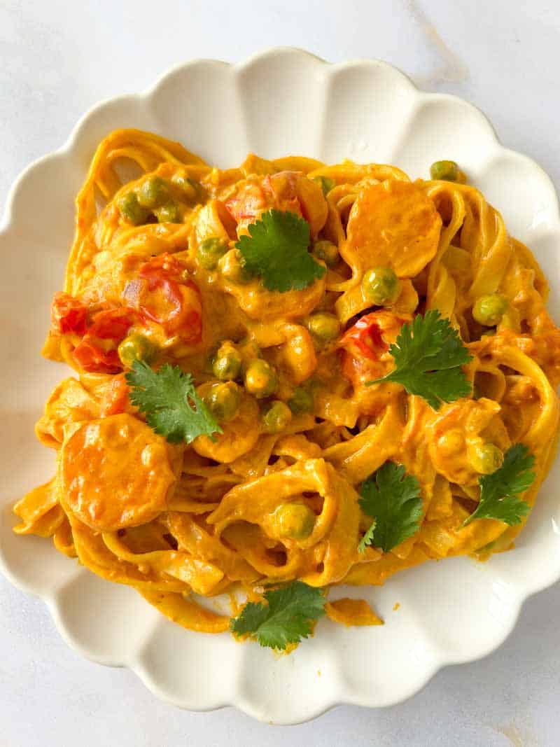 Curry pasta on a plate with coriander leaves.