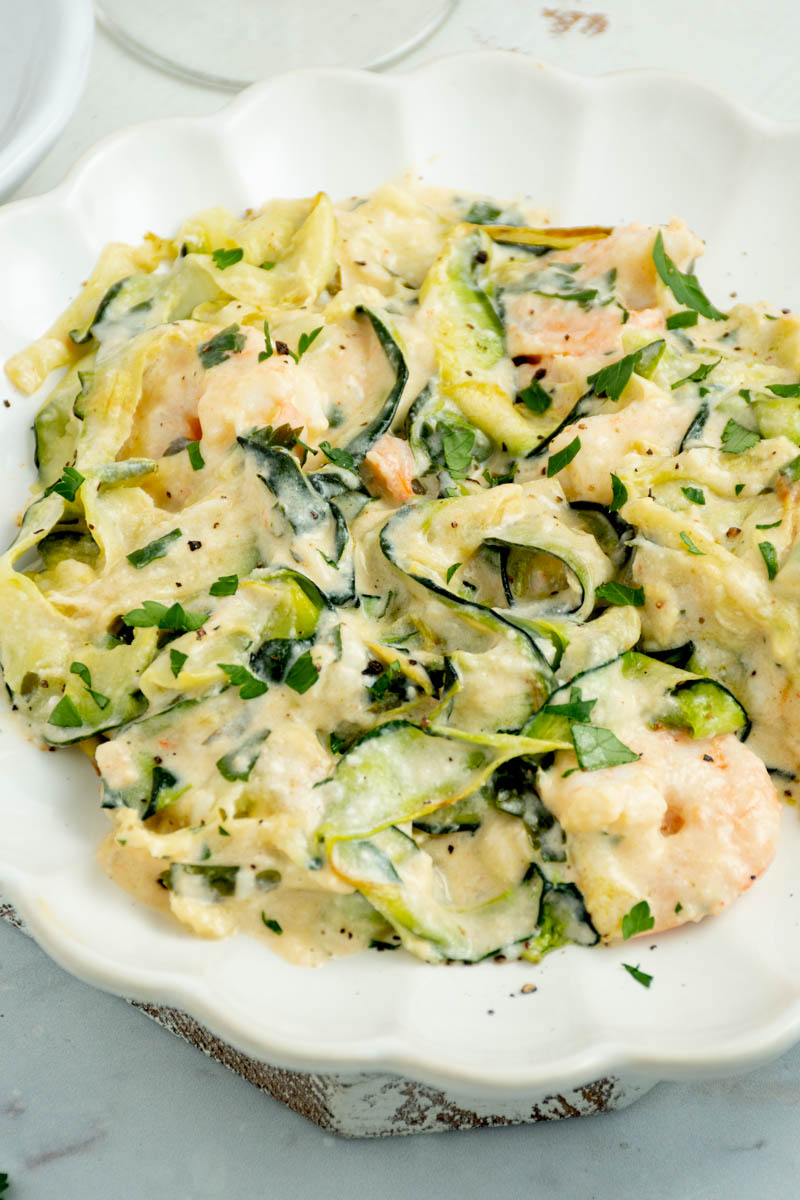 Zucchini and shrimp tagliatelle on a white plate.