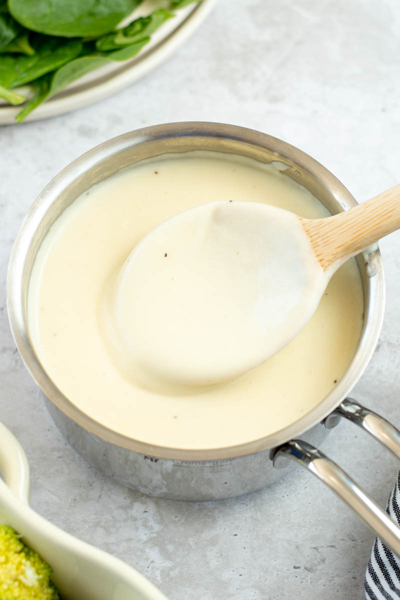 Béchamel dans une casserole avec une cuillère en bois.