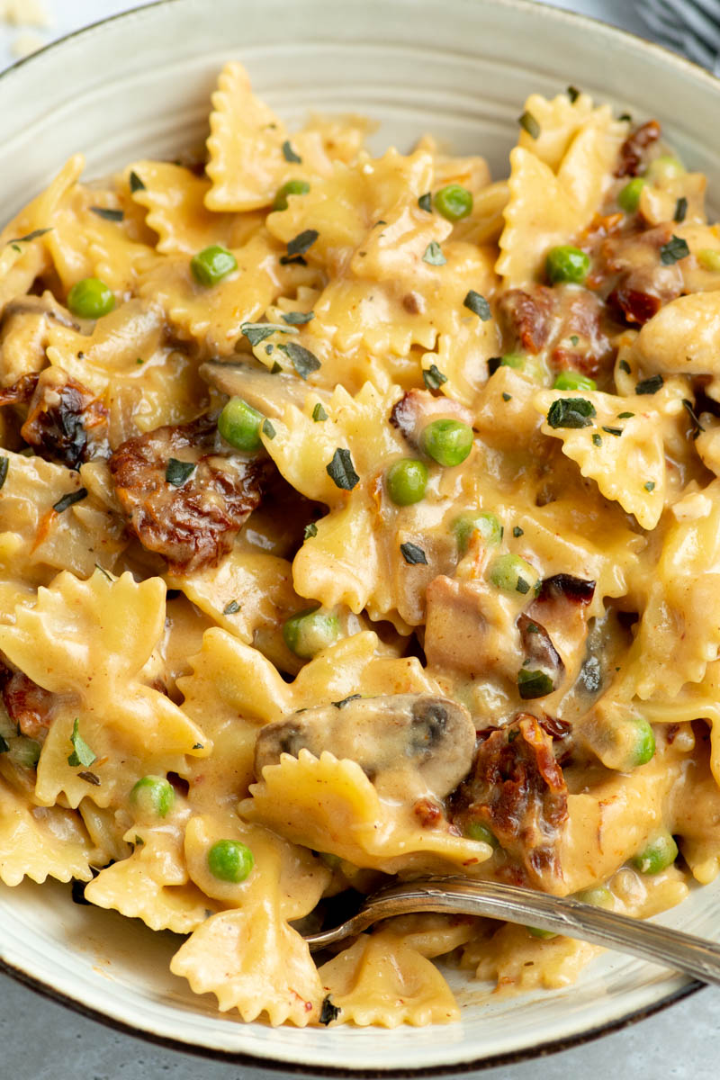 Creamy Farfalle with chicken and roasted garlic in a grey bowl.