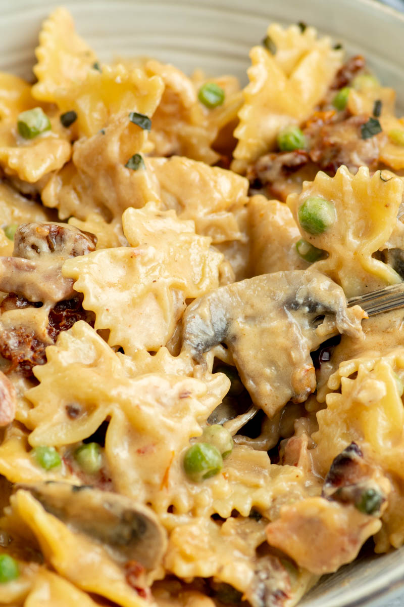 Creamy Farfalle with chicken and roasted garlic in a grey bowl.