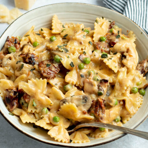 Creamy Farfalle with chicken and roasted garlic in a grey bowl with a fork.