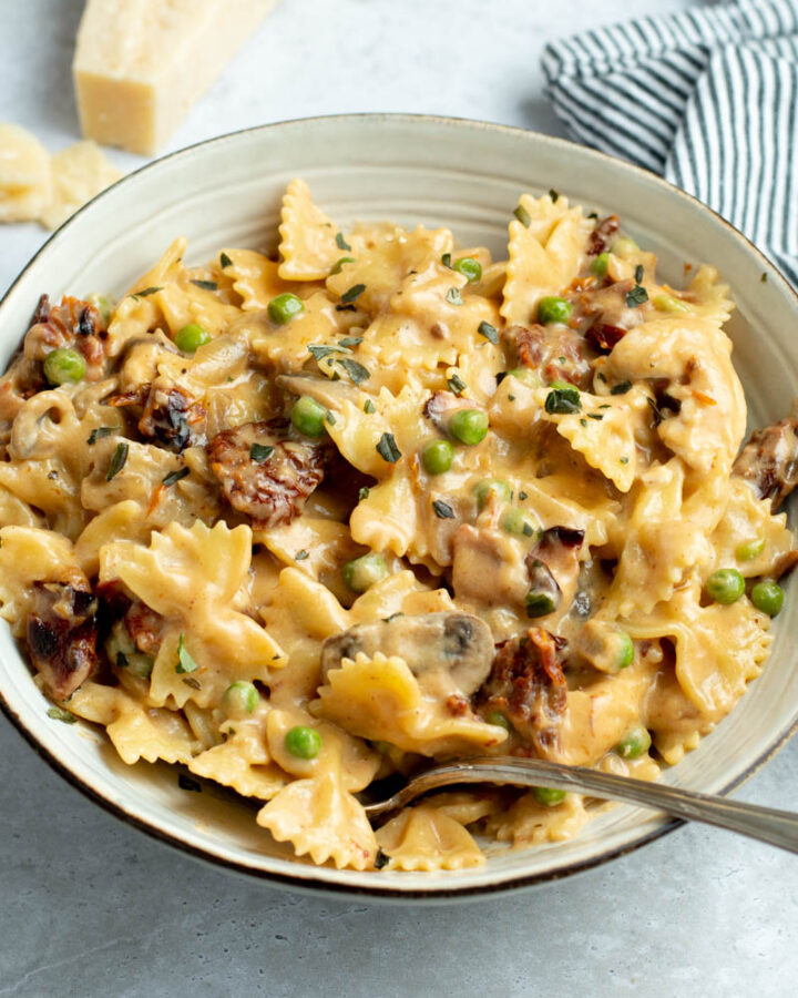 Creamy Farfalle with chicken and roasted garlic in a grey bowl with a fork.