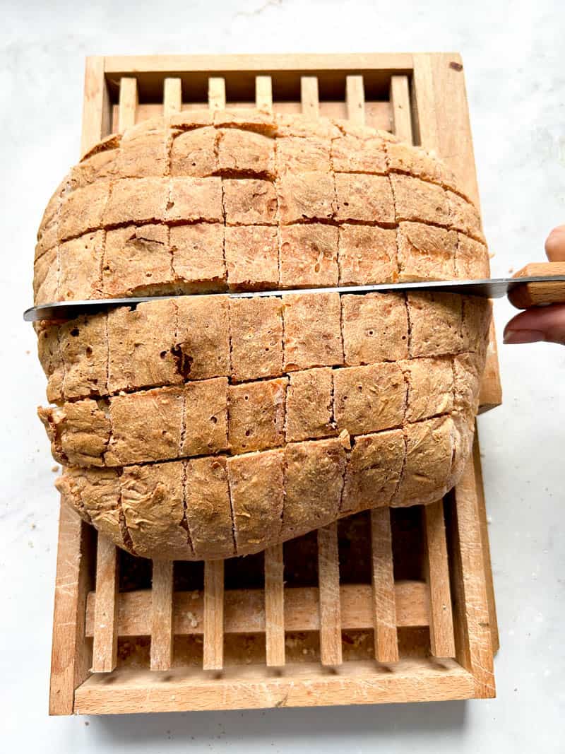 Knife cutting bread loaf widthwise.