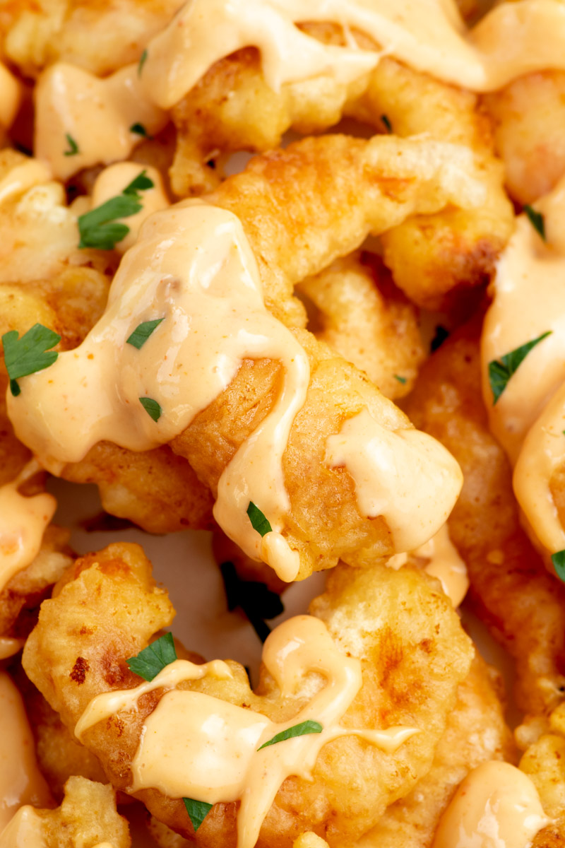 Zoom on a crispy fried shrimp with boom boom sauce.