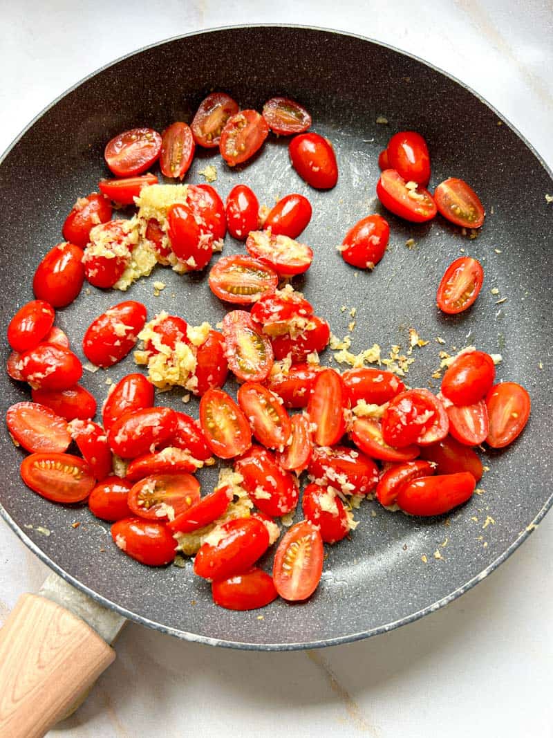 Cherry tomatoes added to the pan with minced and cooked garlic and onion.