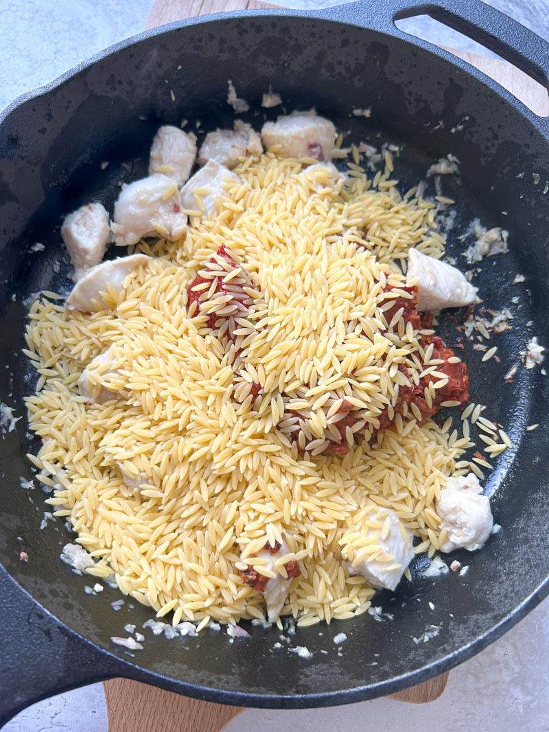 Orzo added to the cast iron skillet.