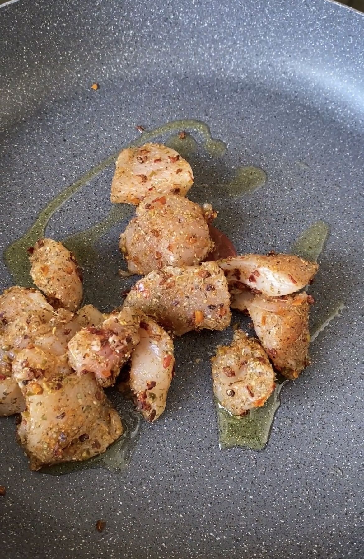 Chicken cubes cooked in a pan with olive oil.