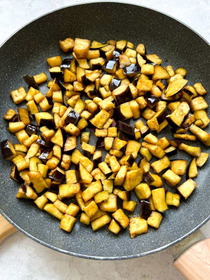 Pré-cuisson des cubes d'aubergine dans une poêle.