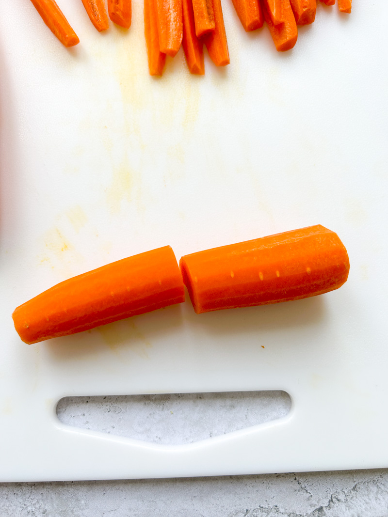 Carrot cut in half crosswise on a white cutting board.