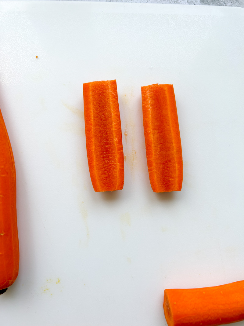 Carrot cut in half lengthwise on a white cutting board.