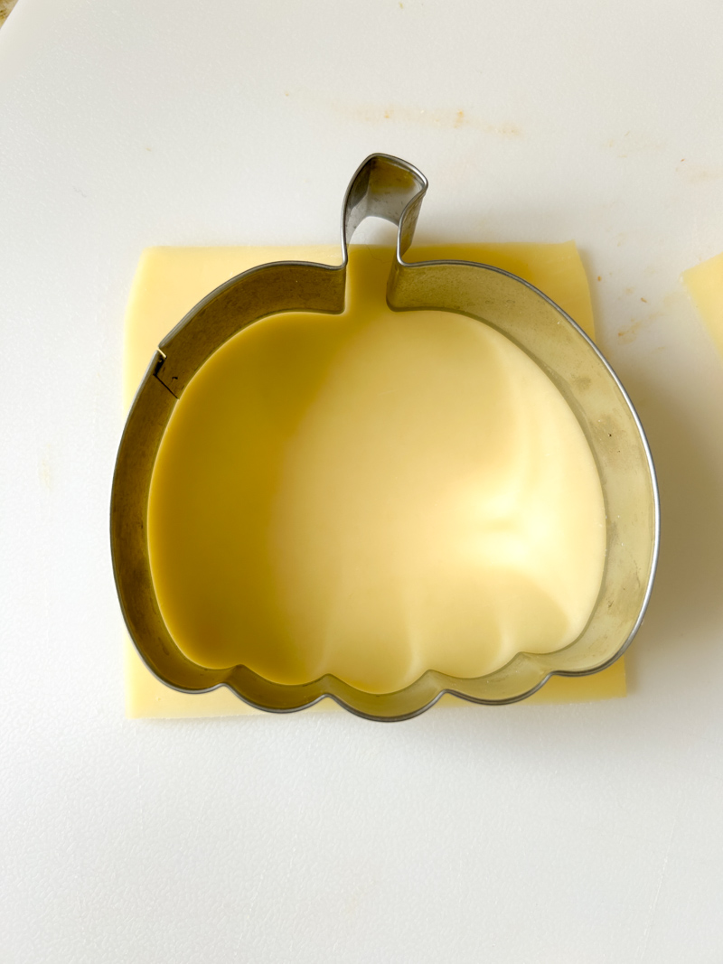 Pumpkin cookie cutter on a slice of gouda cheese.