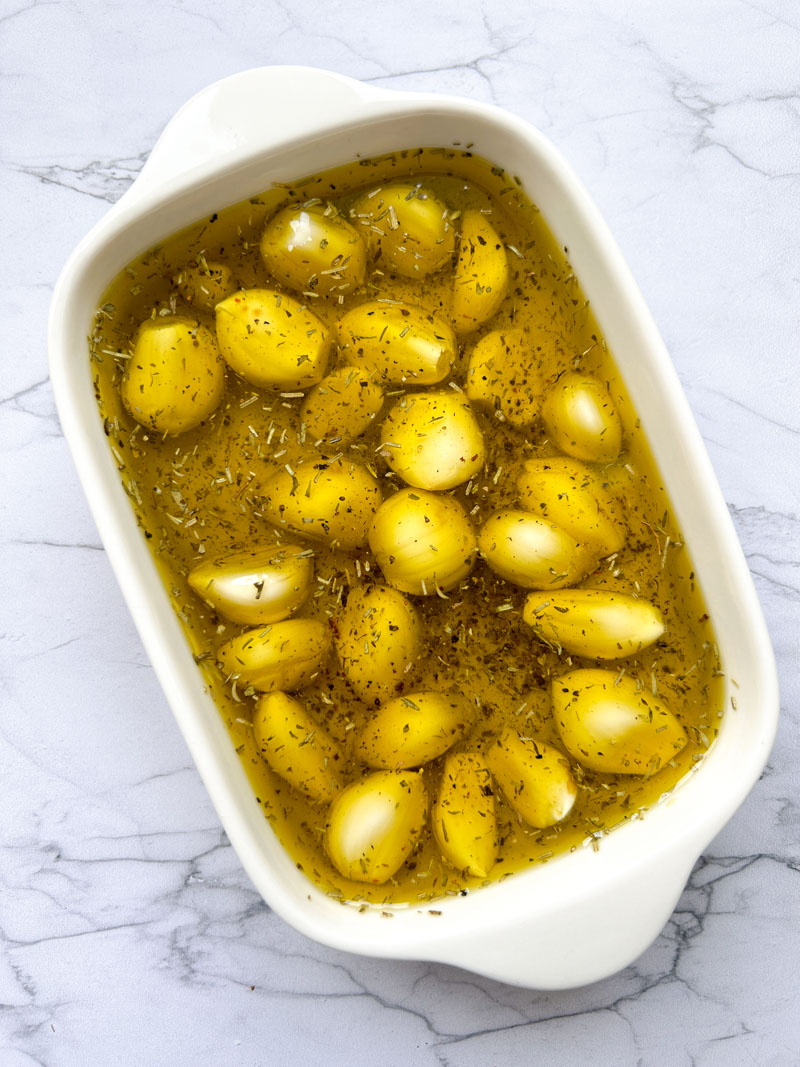 Fresh garlic cloves submerged with olive oil mixture.