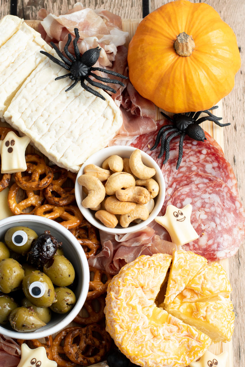 Halloween charcuterie board with cheeses, charcuterie, pumpkins, olives with eyes, mini ghosts, spiders...