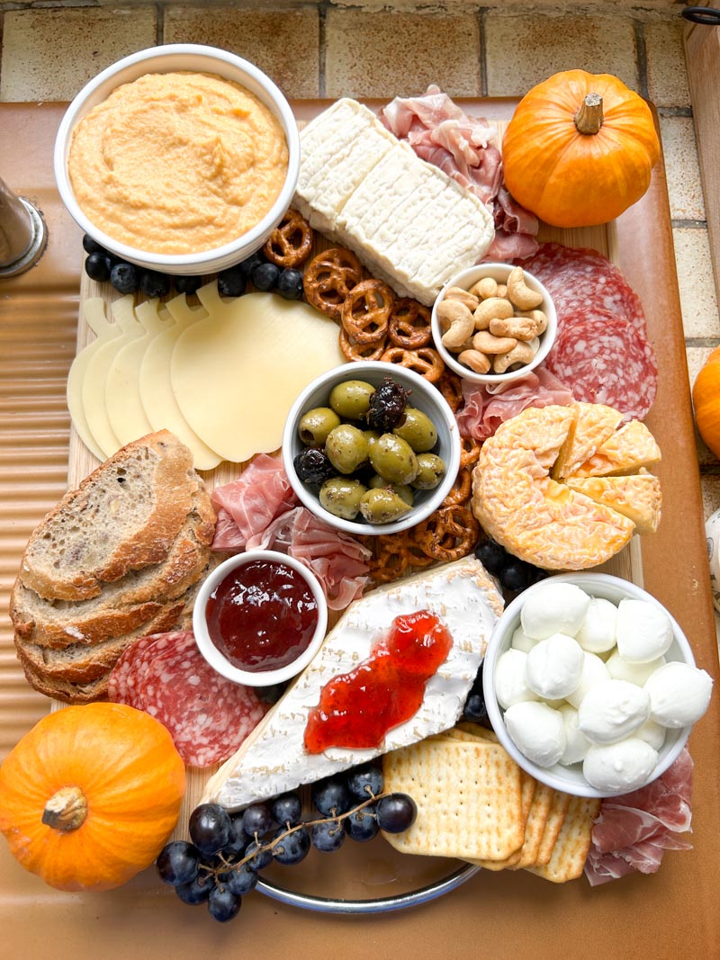 Bowls filled with butternut squash hummus, olives, mozzarella balls and jam on the Halloween Charcuterie Board.