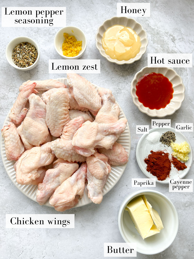 Ingredients of the honey lemon pepper wings in white and beige bowls and plates.