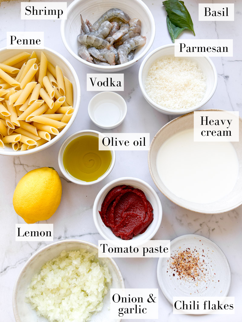 Ingredients of penne alla vodka with shrimp in white and beige bowls.