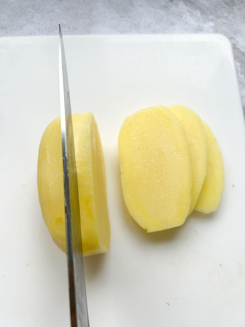 Un couteau qui coupe une pomme de terre en lamelles.