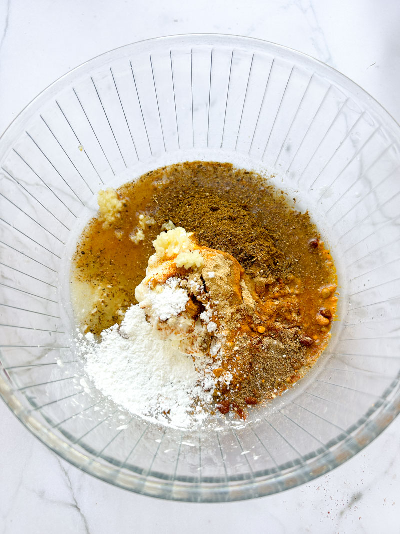 Mix of Tandoori spices and yogurt in a transparent bowl.