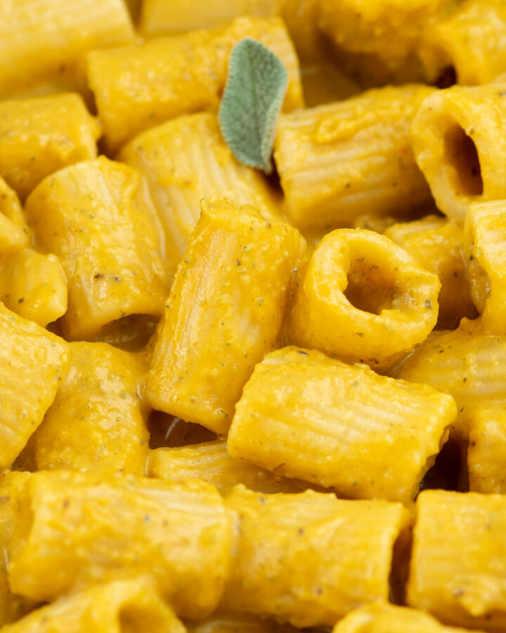 Creamy butternut squash mac and cheese in a frying pan with fresh sage leaves.