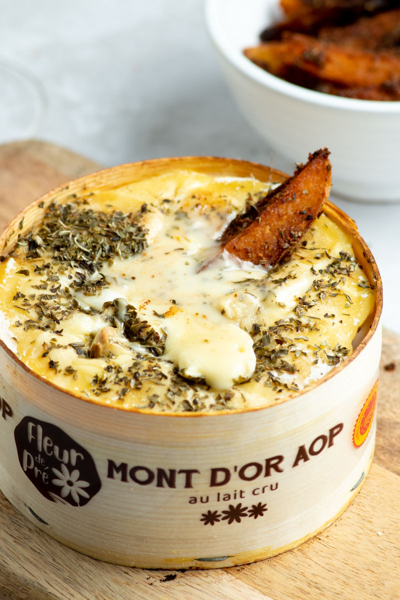 Vacherin Mont d'Or cuit au four avec du fromage crémeux et coulant et des pommes de terre épicées.