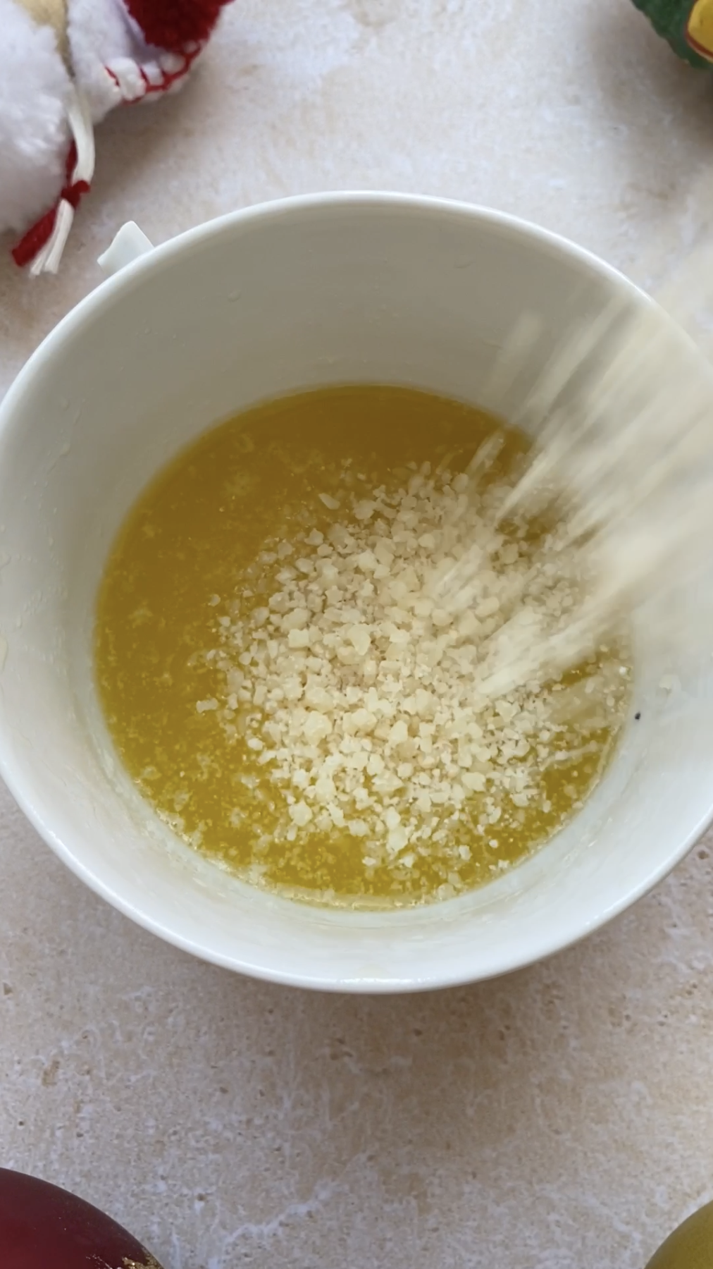 Freshly grated Parmesan cheese falling in a bowl of melted butter.