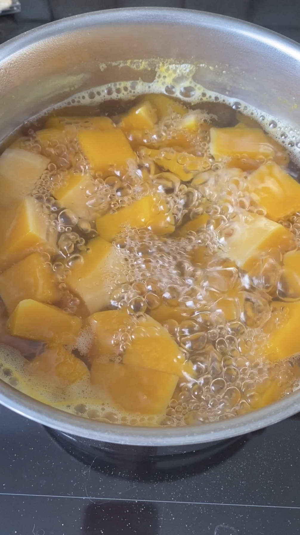 Butternut squash cubes cooking in a pot of boiling water.