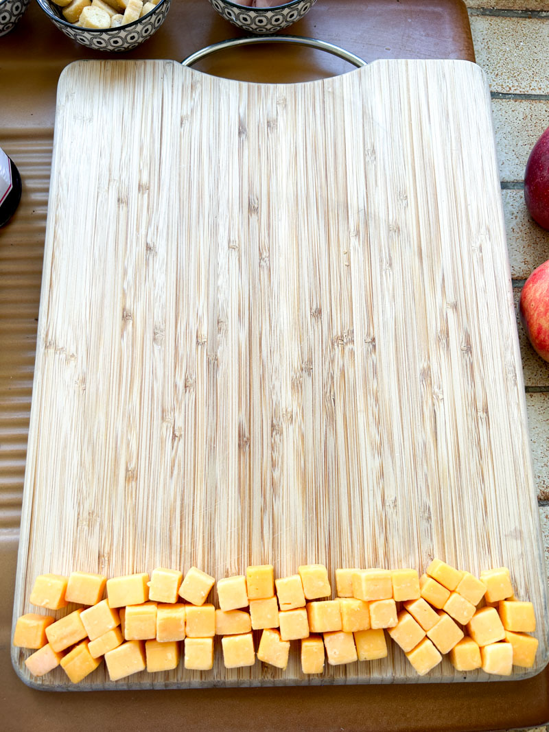 Cheddar cubes placed on a wooden cutting board.