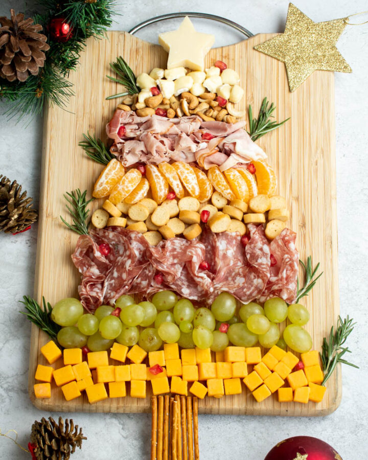 Fromages, viandes, fruits et noix sur une planche à découper en bois, pour former une planche de charcuterie festive sur le thème de Noël.