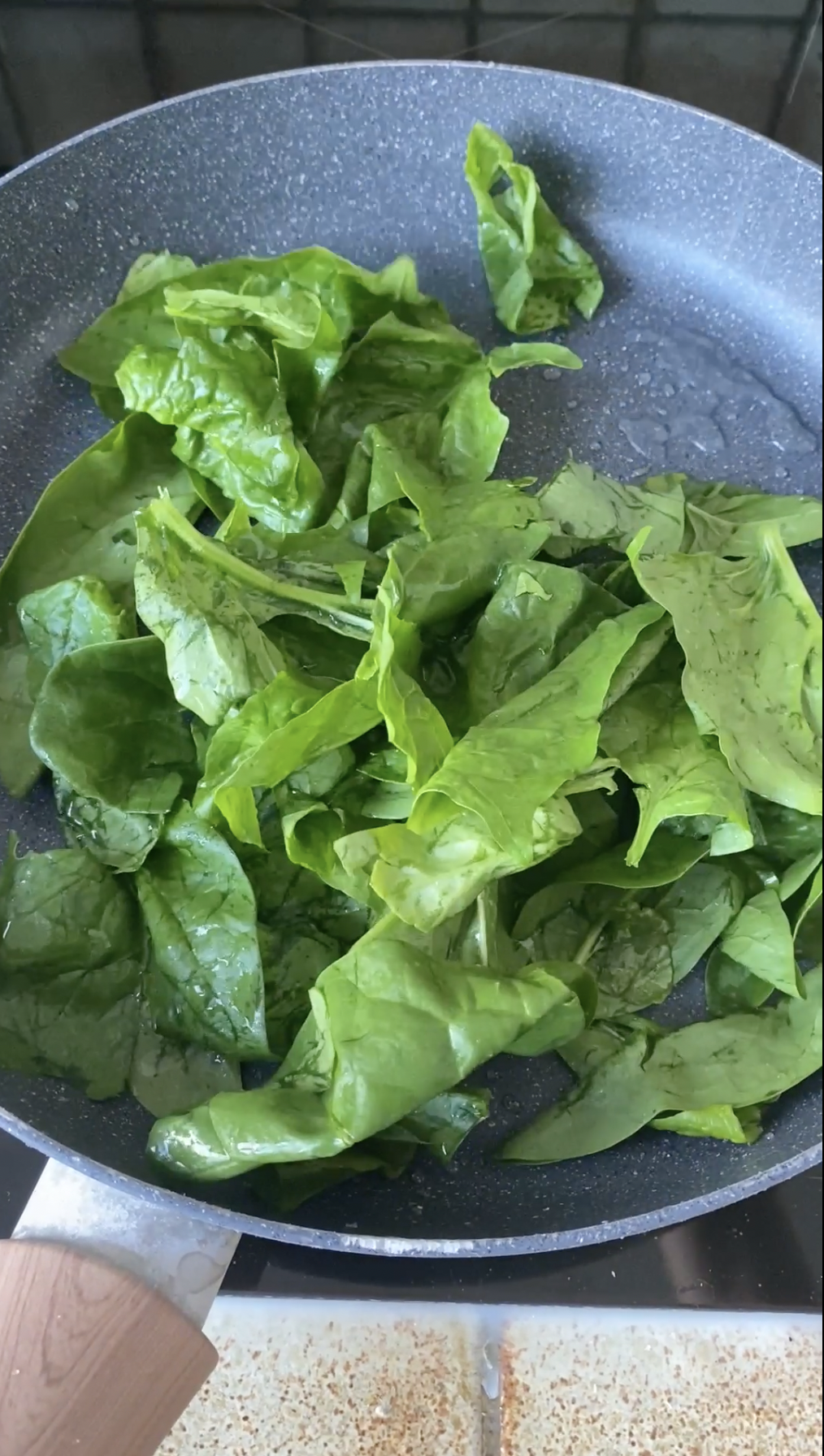 Fresh spinach cooking in a frying pan.