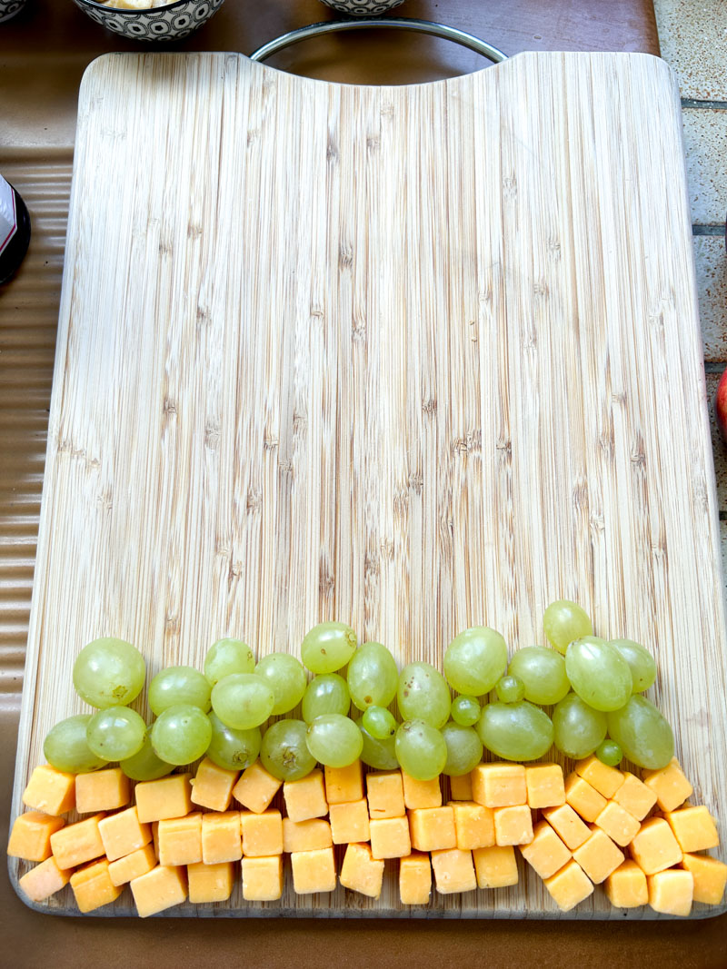 Green grapes added to the wooden cutting board.