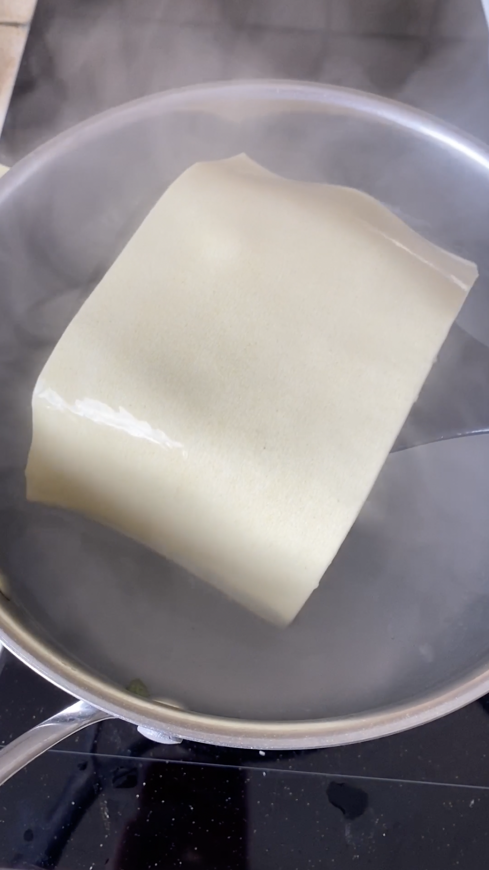 Feuille de lasagne sortant d'une casserole d'eau bouillante.