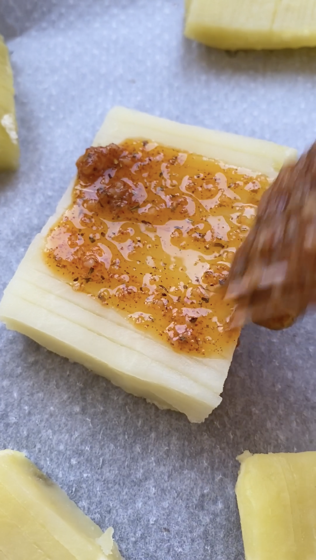 Un pinceau en silicone qui étale le mélange de beurre sur les pommes de terre en accordéon.