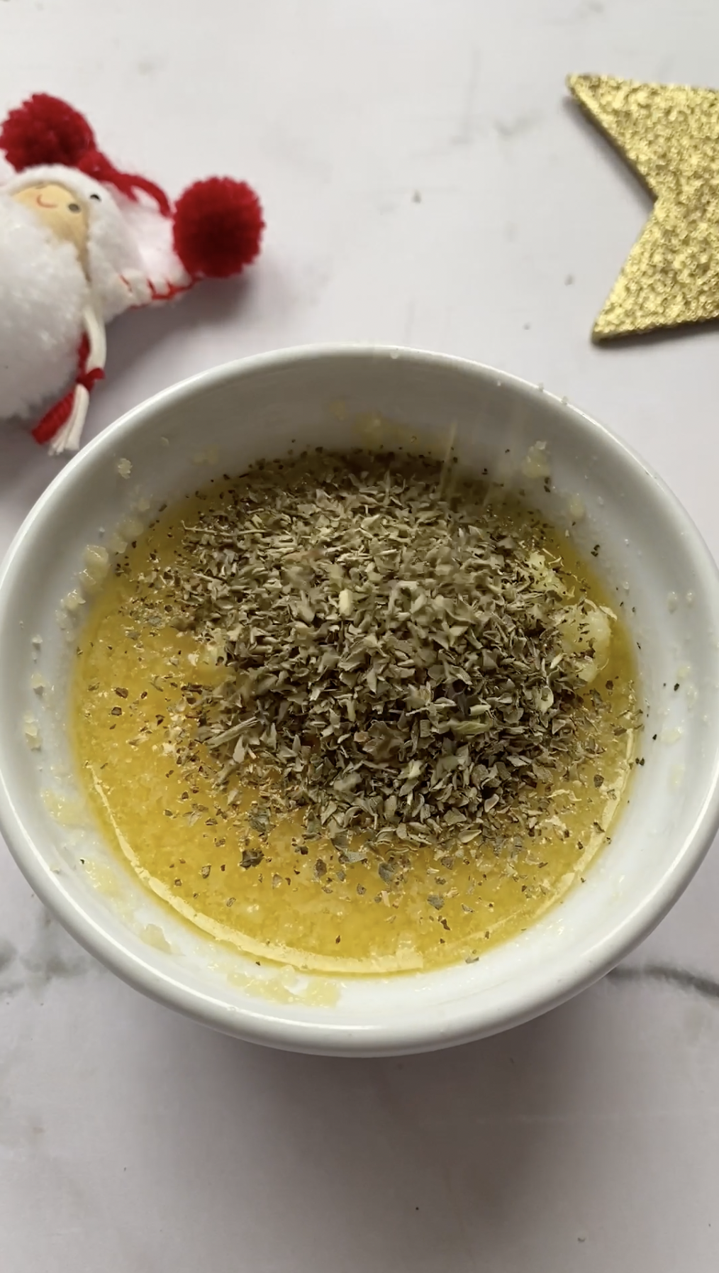 Oregano added to the bowl of melted butter.