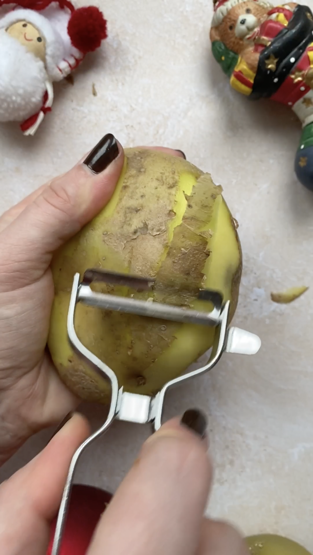 Vegetable peeler hold by a hand, peeling a potato.