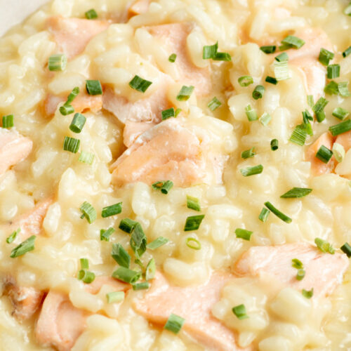 Creamy salmon risotto with chives in a beige bowl.